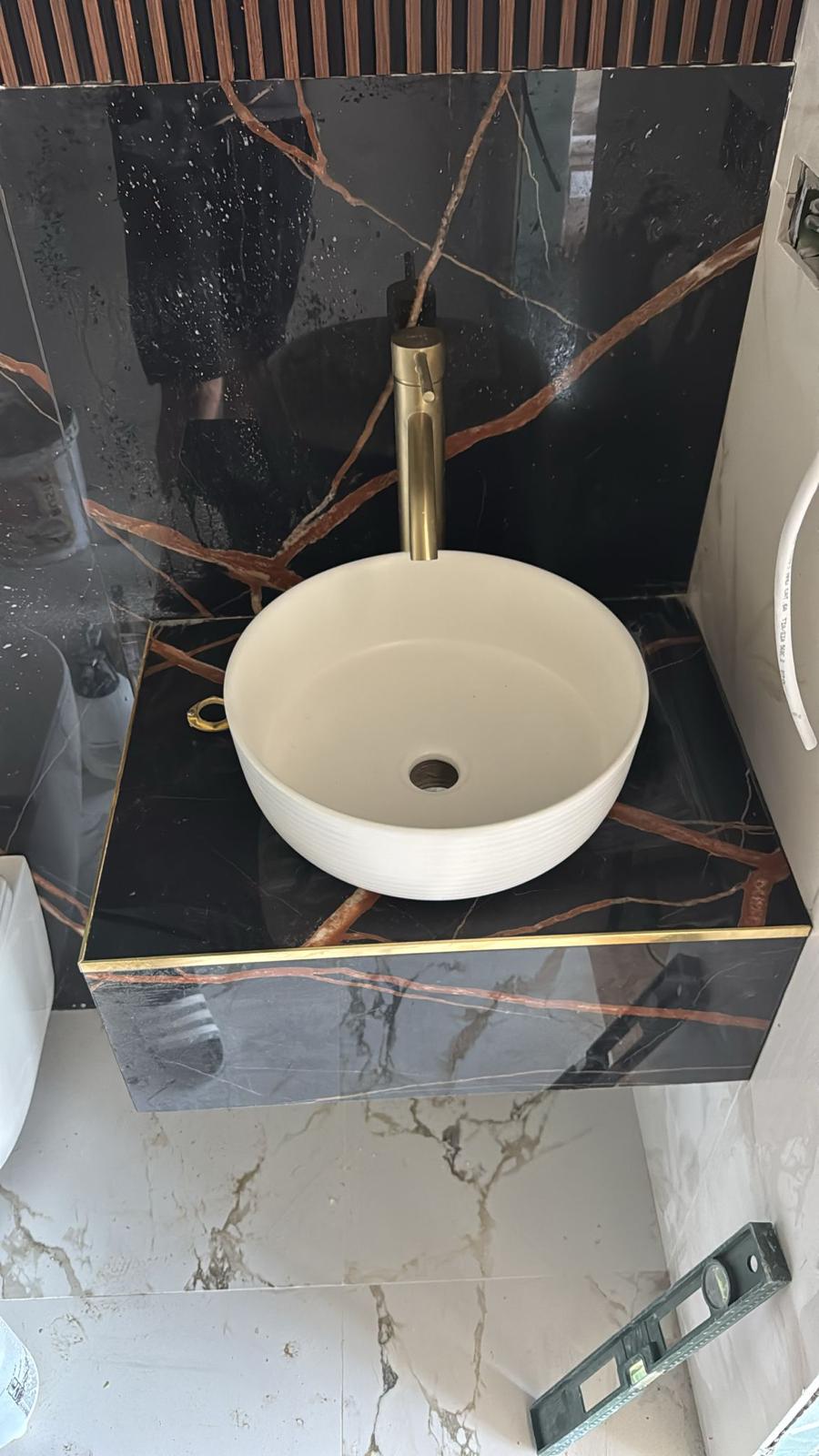 Blat de baie din marmură neagră Sahara Noir cu chiuvetă ceramică și baterie aurie – lucrare realizată de Eugen Arginta